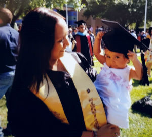 Graduation day - Priscilla DeAndra holding a baby wearing a graduation cap - BSN graduate